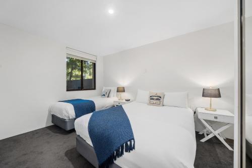堪培拉麦卢卡公园服务公寓的白色客房的两张床,设有窗户