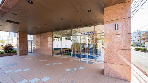 川口市Toyoko Inn Kawaguchi Ekimae的一座带玻璃门的前方商店大楼