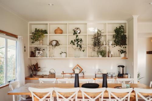 罗托鲁瓦Paradise Valley Lodge的用餐室配有桌椅和植物架子