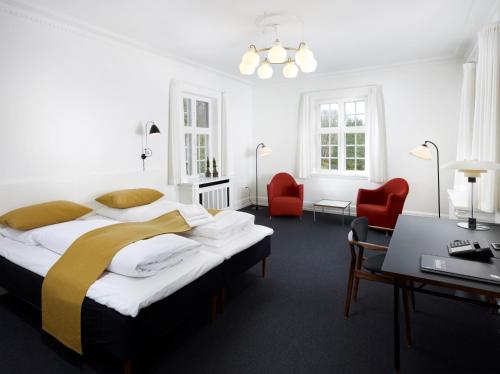 Skarrild斯凯里尔之家西纳图尔会议中心酒店的一间卧室配有一张大床和两张红色椅子