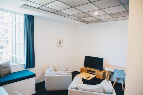 惠灵顿Liberty Apartment Hotel的客房设有一张沙发和一张带电视的书桌。