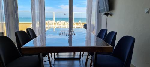 Saint-MarcoufRelais des îles Saint Marcouf的配有桌椅的用餐室,享有海滩美景