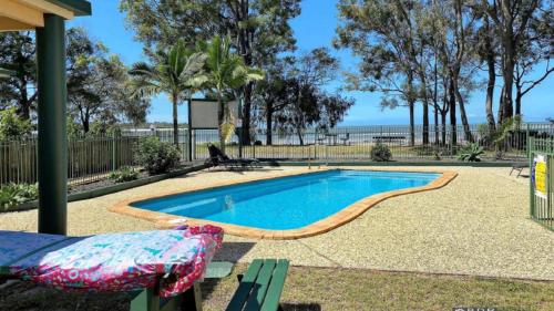 Burrum HeadsSan Marco Villa Close To Beach的游泳池前面设有长凳