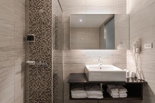 高雄佑煦行旅的浴室配有盥洗盆和带镜子的淋浴