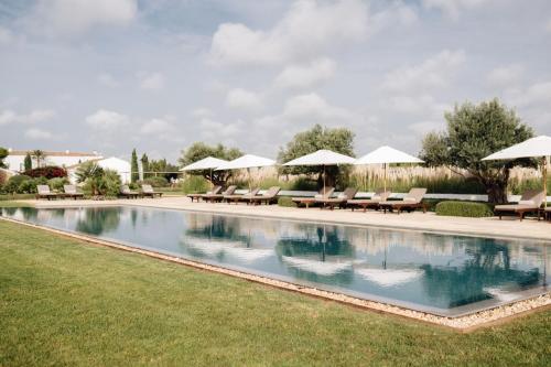 卡拉恩波特Torralbenc, a Small Luxury Hotel of the World的庭院内带椅子和遮阳伞的游泳池