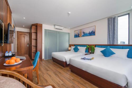 岘港Sea Wind Hotel by THG的酒店客房设有两张床和一张桌子。