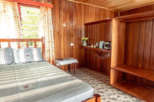 Leleana Resort Kolombangara Island的木制客房内的一间卧室,配有一张床