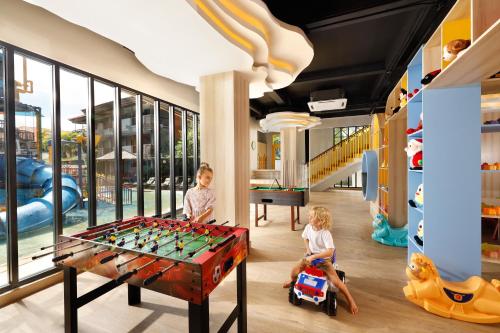 库塔巴厘岛王朝假日酒店的两名儿童在带桌上足球的游戏室玩耍