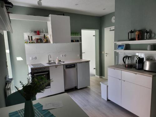 沃梅尔斯泰德Exquisite, gemütliche kleine Wohnung mit Balkon的厨房配有白色橱柜、水槽和炉灶。