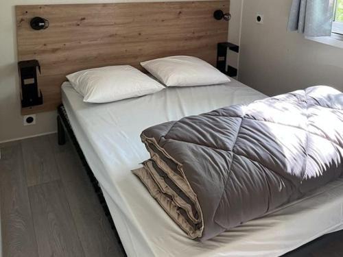 罗卡马杜尔Camping les Cigales Rocamadour的卧室内的一张带白色床单和枕头的床