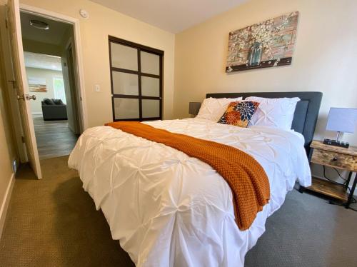 卡拉马祖2 BR Family Friendly Nature Getaway near Golf Course的一间卧室配有一张大白色床和橙色毯子