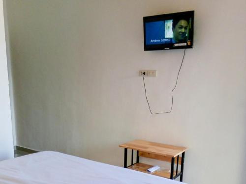 SinapuranRedDoorz @ Sihole Paradise Inn Parbaba的卧室设有壁挂式电视和桌子。