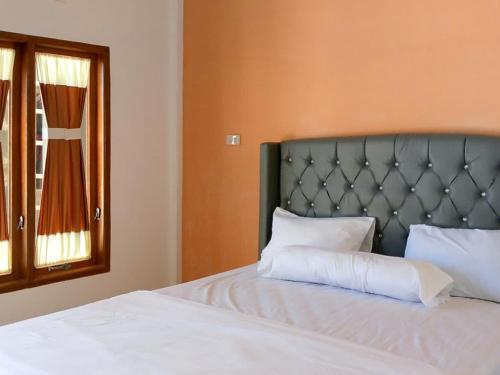 SinapuranRedDoorz @ Sihole Paradise Inn Parbaba的卧室配有带白色枕头的床和窗户。