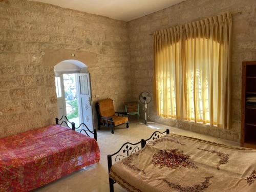 伯利恒Dar Ateeq's Arches/ Bethlehem Apartment的一间卧室设有两张床、一把椅子和一个窗户。