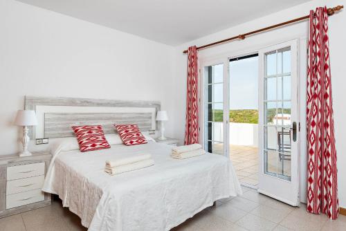 马翁Villa Cala Llonga的一间卧室配有一张带红色枕头的床