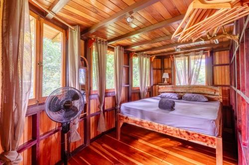 PlatanilloParadiselodge Jungleguesthouse的树屋的卧室配有一张床和风扇