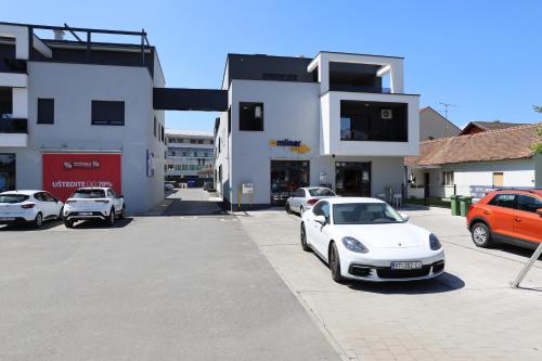 维罗维蒂察Apartman Panonica的停在大楼前停车场的白色汽车