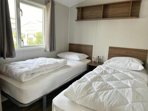 荷属圣马丁Chalet 572 op Recreatiepark De Wielen的带窗户的客房内设有两张单人床。