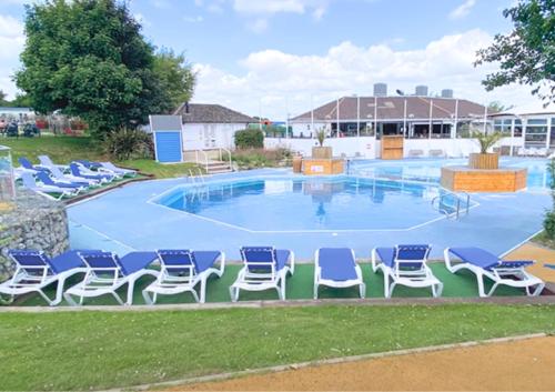 罗切斯特Haven Holiday Home at Kent Coast Allhallows的一个带蓝色椅子的大游泳池