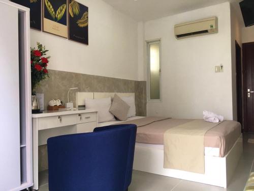 胡志明市Saigon Cozy Hotel的一间卧室配有一张床、一张桌子和一把蓝椅