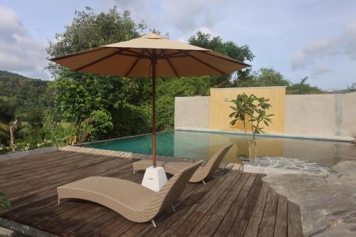 康提Stone Cottage的游泳池旁的甲板上配有两把椅子和一把遮阳伞