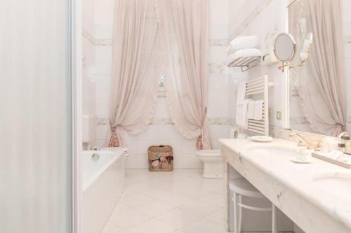 费拉拉Duchessa Isabella Collection by Uappala Hotels的白色的浴室设有浴缸、卫生间和水槽。
