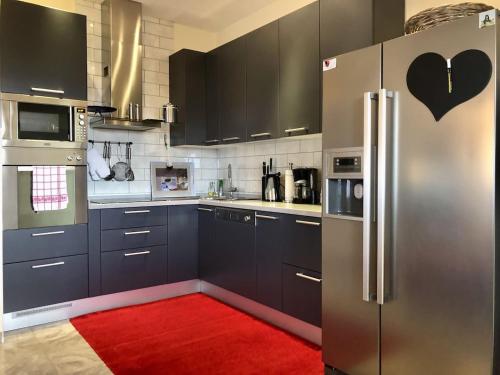 普莱克Wohnung mit Meerblick Romy的厨房配有不锈钢冰箱和红色地毯