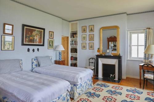 DoudevilleLa maison d'Hector的一间卧室设有两张床、一个壁炉和一个镜子