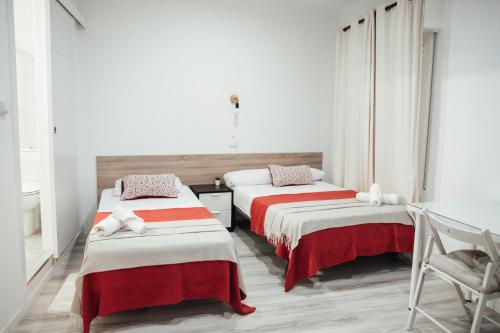巴塞罗那鲁塔弗朗西亚旅馆的配有红色和白色床单的客房内的两张床