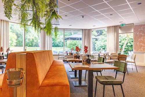 洛赫姆斯切拍思康弗莱彻餐厅酒店 的餐厅设有桌椅和窗户。