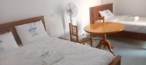 AwasiAster Suites Kisumu的一间卧室配有两张床、一张桌子和一张书桌
