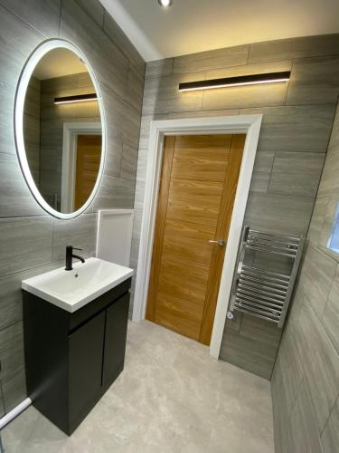 斯旺西Walter Road Holiday Home Swansea - 4 bedrooms的一间带水槽、镜子和门的浴室