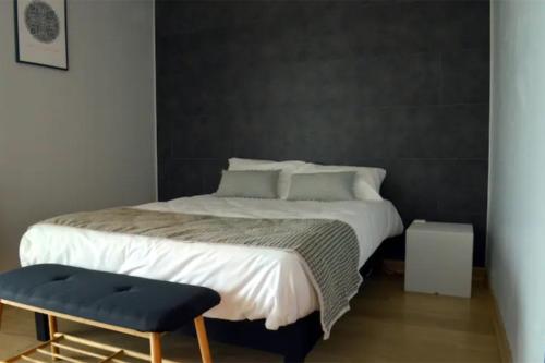 普瓦捷Maison St Eloi by iZiLi *Futuroscope*Jardin*的一间卧室设有一张大床和一张蓝色凳子