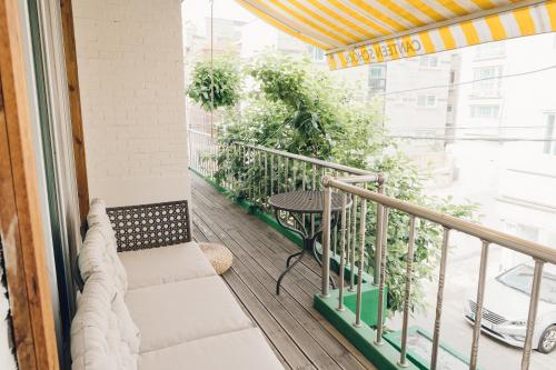 首尔Hongdae Luxury Private Single House with Big Open Balcony Perfect for a Family & Big Group 3BR, 5QB & 1SB, 2Toilet的阳台配有桌子和一些植物