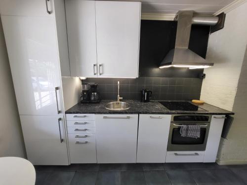 图尔库Saunallinen rivitalon pääty asunto kahdella terassilla的厨房配有白色橱柜和水槽
