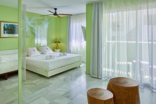 普拉亚登博萨Tropicana Ibiza Suites - Adults Only的卧室设有白色的床和绿色的墙壁