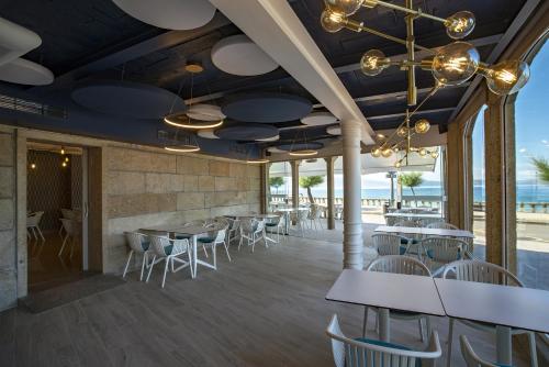 桑亨霍Hotel del Mar的一间带桌椅和海滩的餐厅
