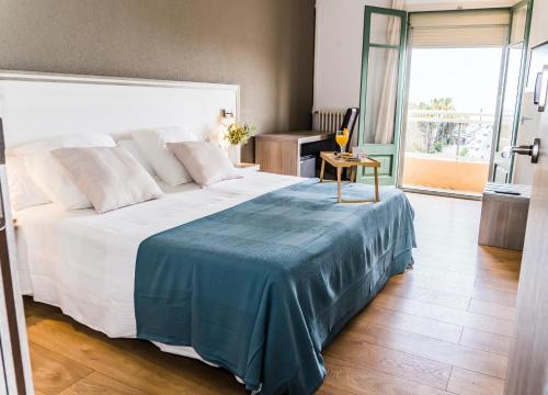 萨洛普拉纳斯酒店的一间卧室配有一张大床,上面有蓝色的毯子