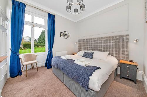 瑟斯克Finest Retreats - Hambleton Hall Apt的一间卧室配有一张带蓝色窗帘的床和一扇窗户