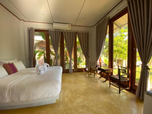 素可泰BaanSuk Sukhothai Resort的卧室设有白色的床和大窗户