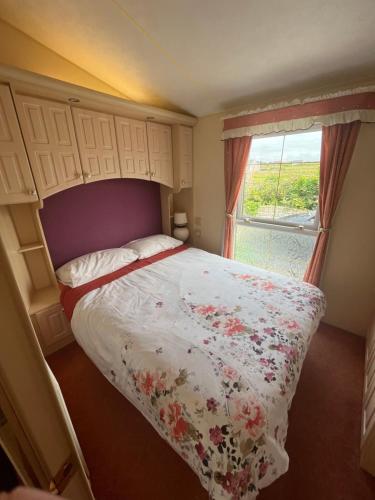 奎尔蒂Seaside Chalet的一间卧室配有一张带花卉床罩的床和窗户。
