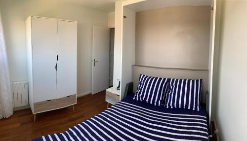 拉卡诺奥肯T2 Rés Océanides vue Océan, parking privé的卧室配有蓝色和白色条纹床和镜子