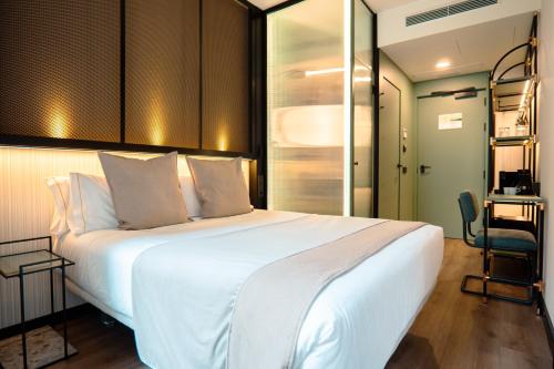 马德里Akeah Hotel Gran Vía的卧室配有一张白色大床和一张书桌