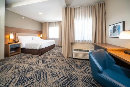 查尔斯顿Candlewood Suites Charleston – Mt. Pleasant, an IHG Hotel的酒店客房,配有一张床和一张蓝色椅子