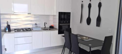 普拉亚Cazinos Apartamento的厨房配有白色橱柜和一张带黑色餐具的桌子