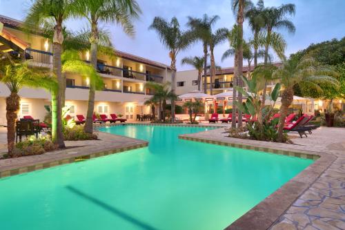 尔湾奥兰治县中庭酒店的一个带棕榈树和椅子的度假游泳池