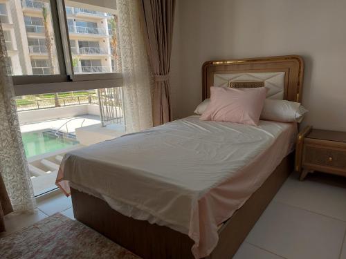 阿莱曼Marassi Marina的窗户客房内的一张带粉红色枕头的床