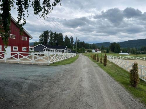 诺托登Gårdsopphold Notodden的一条土路,有红谷仓和白色围栏