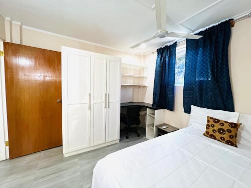 圣乔治SeaLaVie Apartments - Grenada的卧室配有白色的床和蓝色窗帘