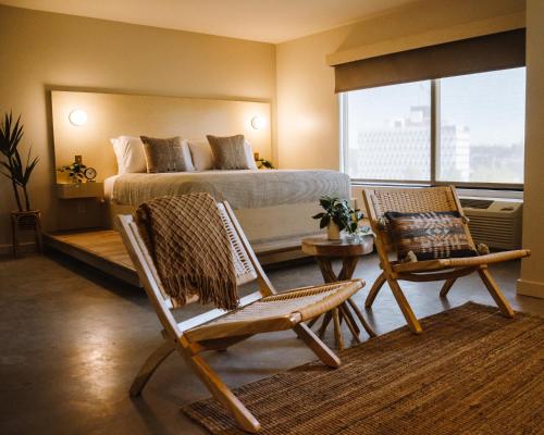 塔尔萨Brut Hotel的一间卧室配有一张床、两把椅子和一张桌子